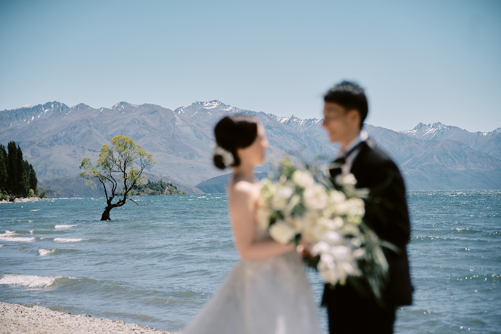 Queenstown Wedding Photographer A bride and groom standing on the shore of Lake Wanaka, New Zealand.